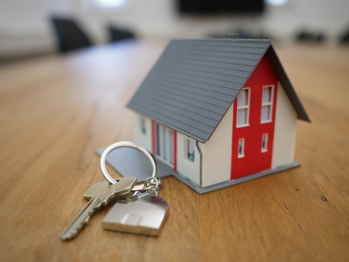 Wohnungsschlüssel neben Miniaturhaus als Symbol für Mietkaution und Übergabe